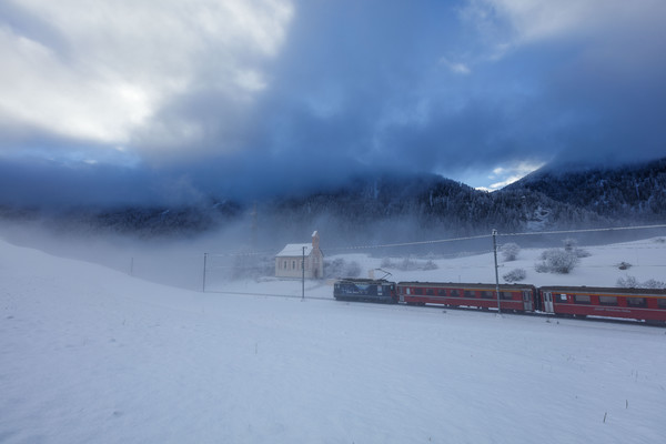 Die Rhätische Bahn unterwegs im Schneegestöber bei Ardez im Unterengadin.