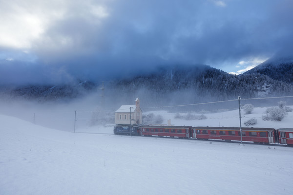 Die Rhätische Bahn unterwegs im Schneegestöber bei Ardez im Unterengadin.