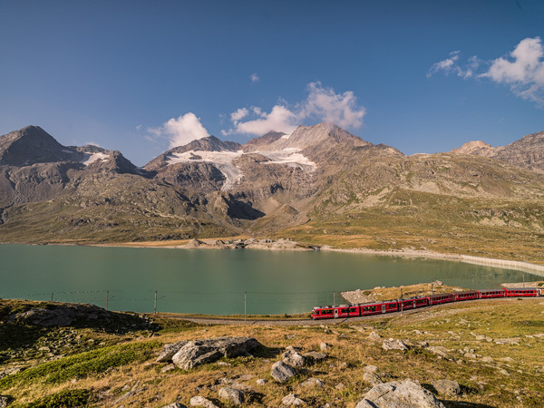 Ein Triebzug der Rhätischen Bahn unterwegs in der hochalpinen Landschaft auf dem Berninapass.