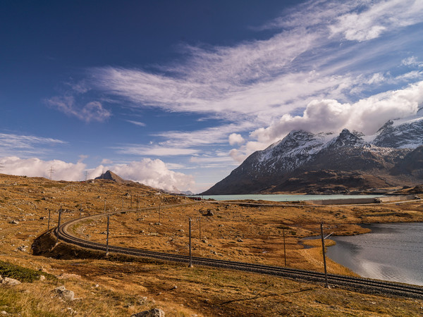 Bernina Express der Rhätischen Bahn unterwegs zwischen Lago Bianco und Lej Nair auf dem Berninapass. Im Hintergrund der Piz Campasc, Sassal Mason und 