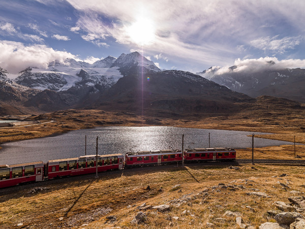 Bernina Express der Rhätischen Bahn unterwegs zwischen Lago Bianco und Lej Nair auf dem Berninapass. Im Hintergrund der Piz Cambrena.