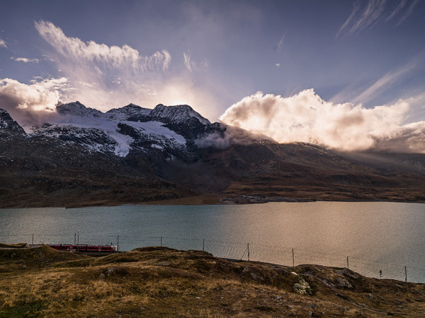 Die Rhätische Bahn unterwegs entlang des Lago Bianco auf dem Berninapass. Im Hintergrund der Piz Cambrena und Piz d'Arlas.