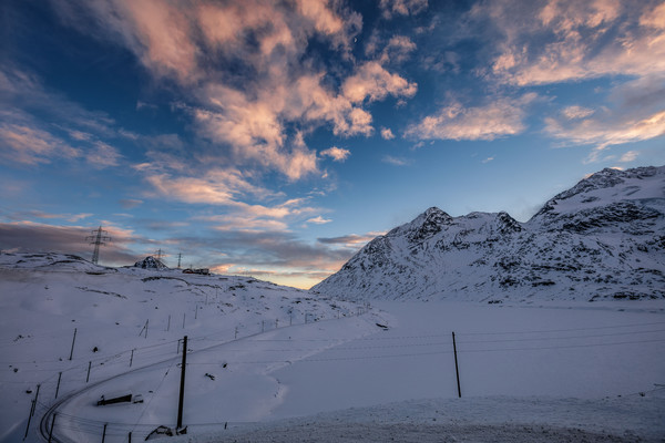 Abendstimmung auf dem Berninapass im Oberengadin. Im Hintergrund der zugeschneite Lago Bianco sowie die Berge Piz Campasc, Sassal Mason, und der Piz C