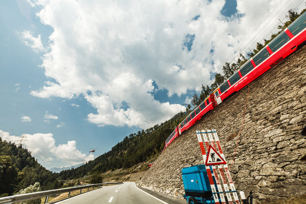Der Bernina Express zwischen Brusio und Miralago. Oberhalb der Strasse Betonierarbeiten mit Hilfe eines Helikopter mit Betonbehälter.