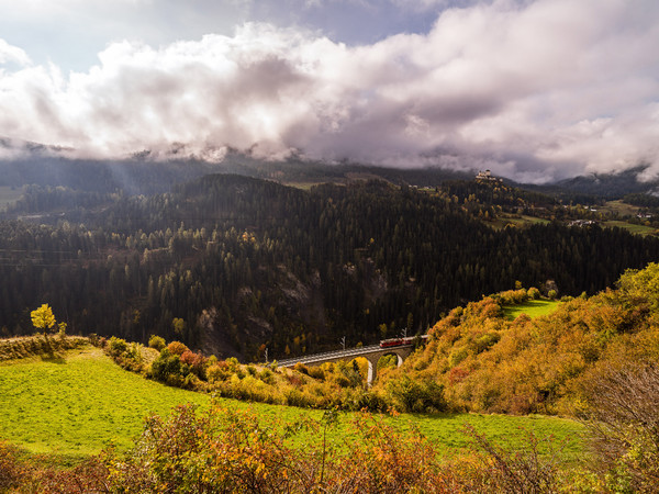 Herbstliche Aussicht von der Strasse nach Ftan auf das Val Corgnanca-Viadukt der Rhätischen Bahn, im Hintergrund das Wahrzeichen des Unterengadins, da