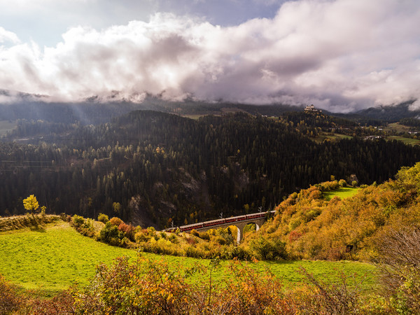 Herbstliche Aussicht von der Strasse nach Ftan auf das Val Corgnanca-Viadukt der Rhätischen Bahn, im Hintergrund das Wahrzeichen des Unterengadins, da