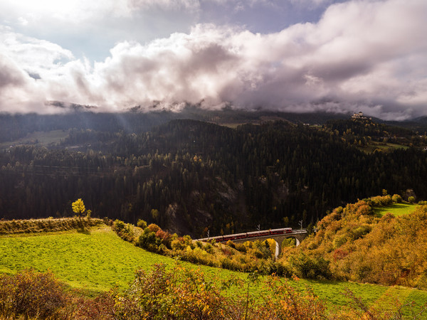 Herbstliche Aussicht von der Strasse nach Ftan auf das Val Corgnanca-Viadukt der Rhätischen Bahn, im Hintergrund das Wahrzeichen des Unterengadins, da