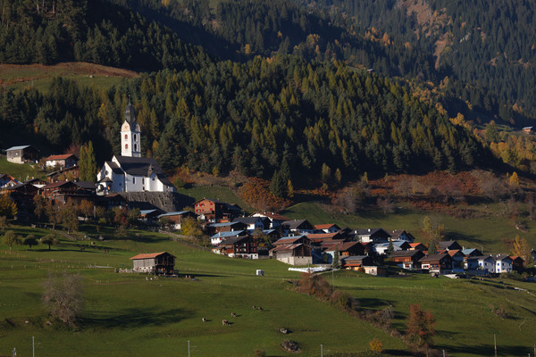 Blick auf das Bergdorf Sumvitg mit seinem markanten Kirchturm in der Abendstimmung im Bündner Oberland, Graubünden, Schweiz.